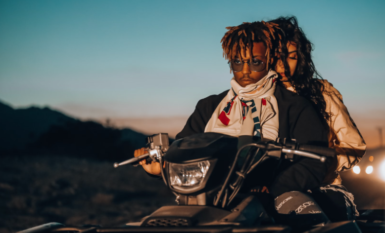 A young man and woman riding a motorcycle in desdesert dusk conveying a sense of adventure and freedom before the festival.