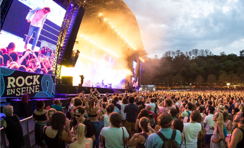 Audience enjoying a live performance at Rock en Seine, an exclusive music festival in Paris, surrounded by the historic elegance of Domaine National de Saint-Cloud.