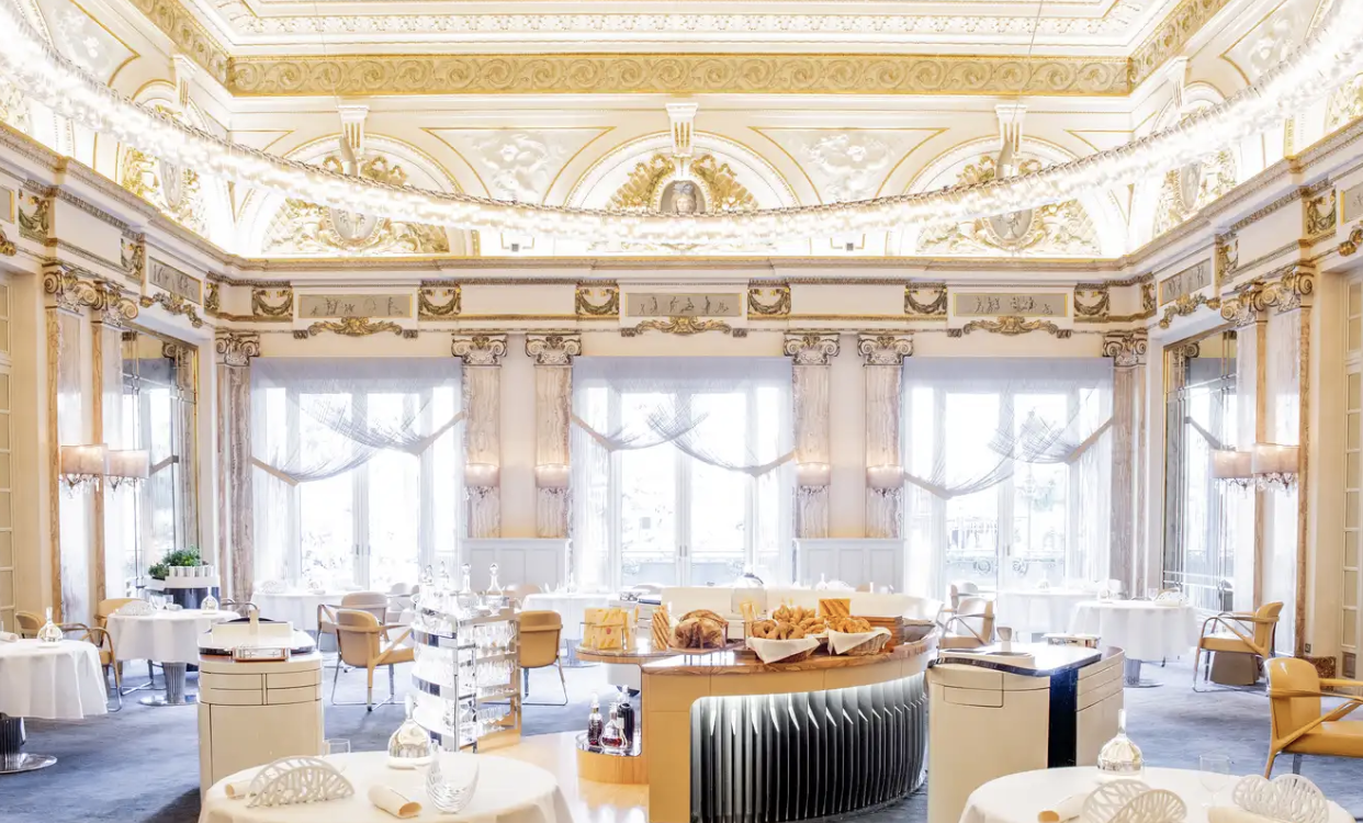 Le Louis XV is a stylish restaurant featuring exquisite gold and white decor, exuding a regal atmosphere and promising an inviting dining experience.