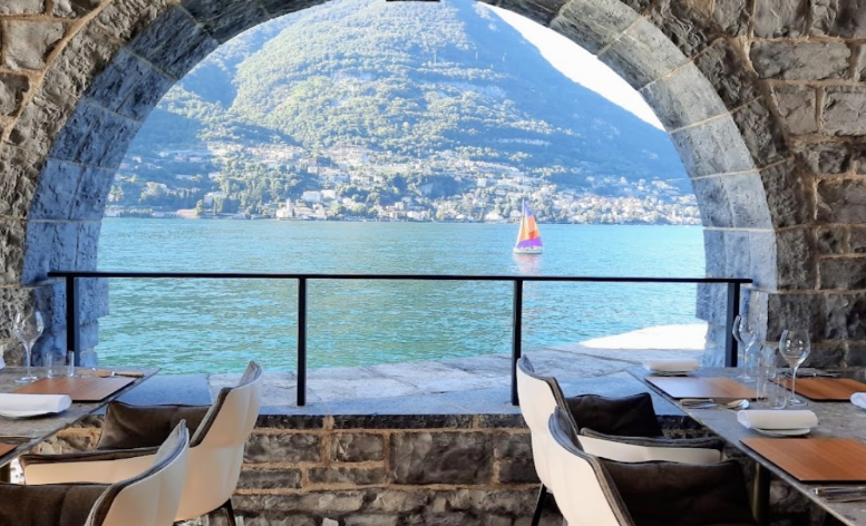 Elegant waterfront dining at Il Sereno al Lago, a Michelin-starred restaurant on Lake Como, featuring stone archways framing panoramic views of the lake and mountains.