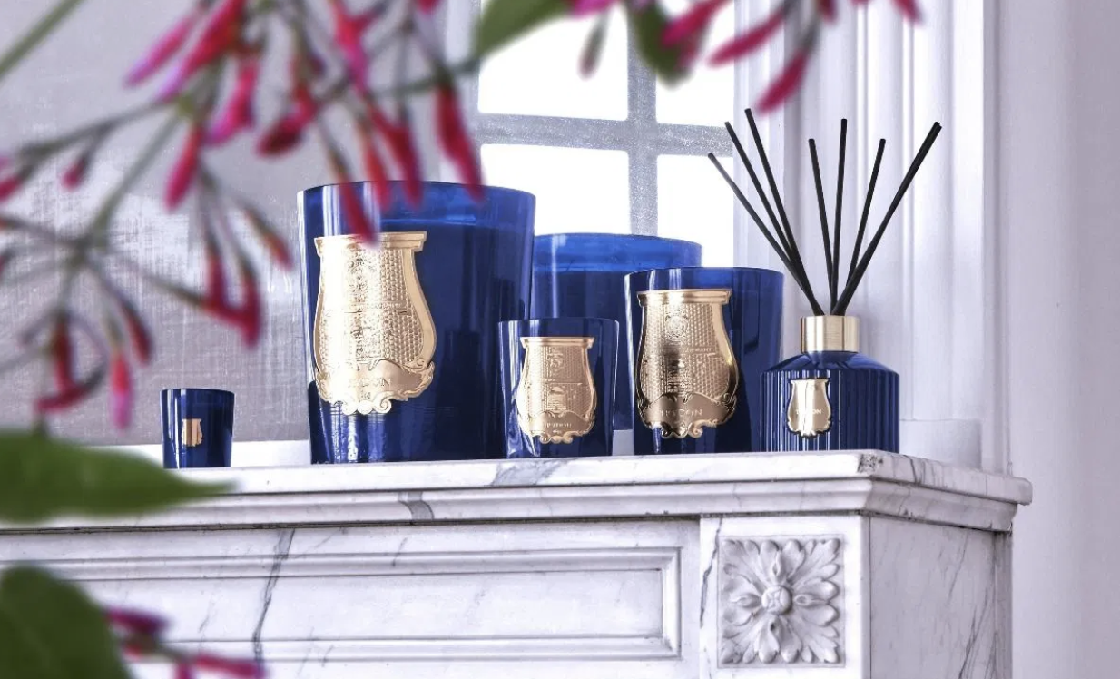 A collection of luxurious Trudon products elegantly arranged on a white marble mantelpiece.