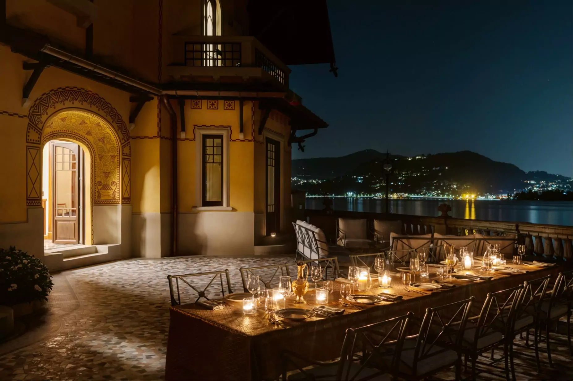 Romantic candlelit dining with lake views at night.