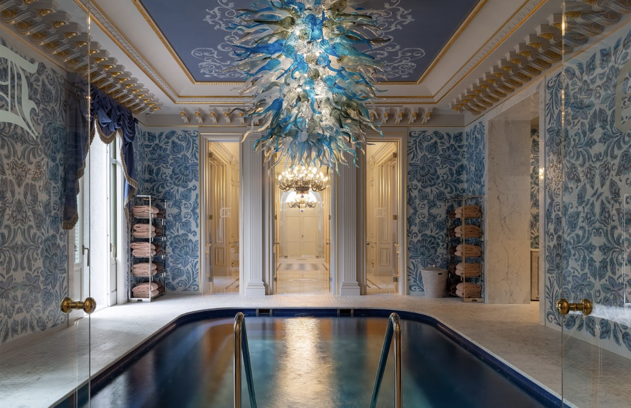 Dale Chihuly glass chandelier above an enclosed pool with tile mosaics.