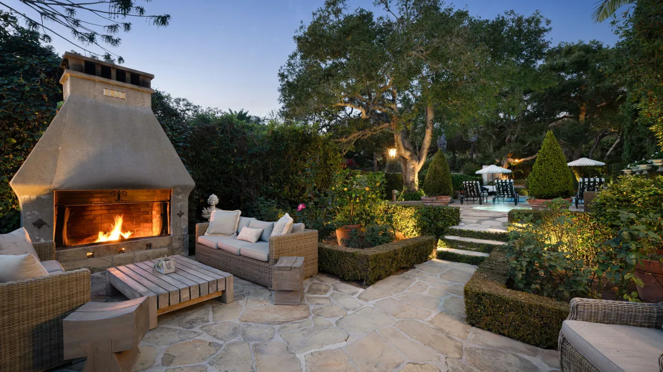 Unwind at this timeless Mediterranean-inspired poolside retreat with manicured hedges, towering palms, and verdant greenery. 