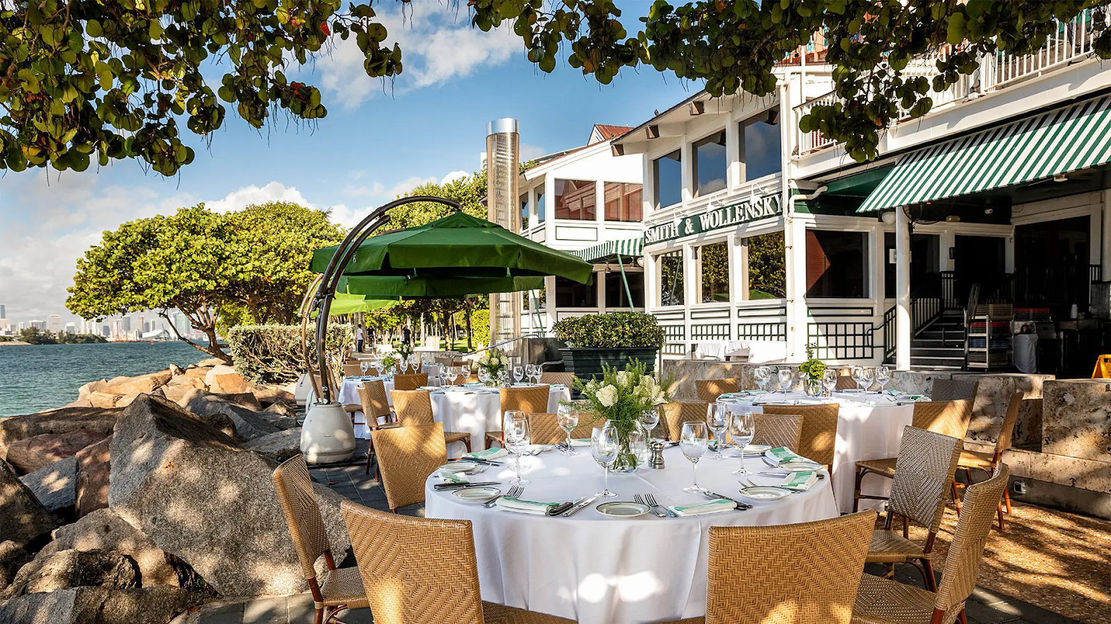 Smith & Wollensky in Miami features elegant outdoor seating, waterfront dining, lush greenery, and panoramic views ideal for luxury waterside dinners.